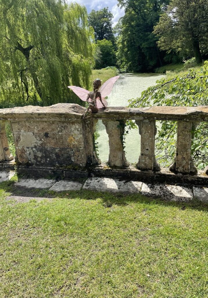 A fairy sitting on the side of a stone bridge.