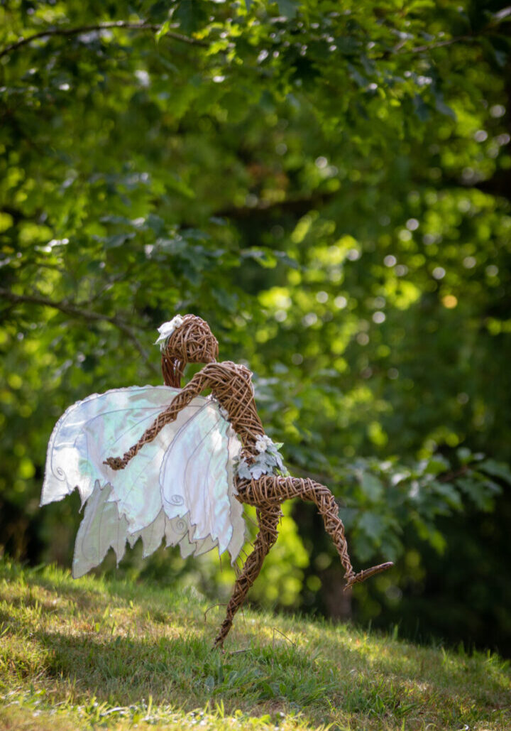 A wire sculpture of an angel in the woods.
